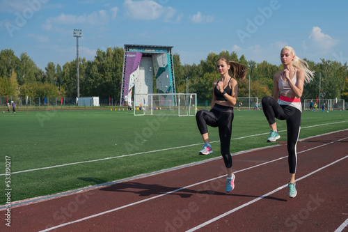 Two athlete young woman runnner are training at the stadium outdoors photo