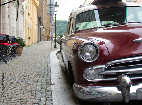 Red retro car parked on a paved European street close-up
