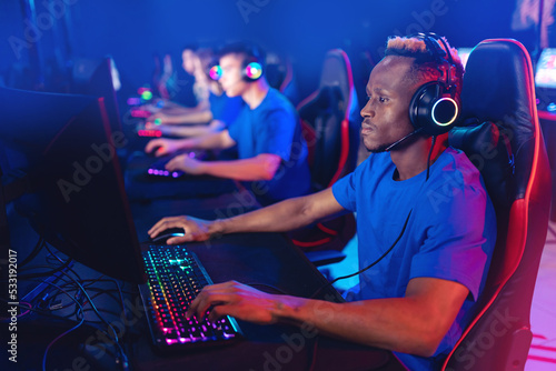 Streamer african young man with team rejoices in victory professional gamer playing online games computer with headphones, neon color