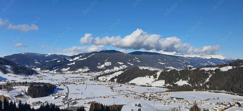 Panorama of the snow-capped Alps and the view of the village of Flachau in Austria from the ski run, on a sunny winter day.