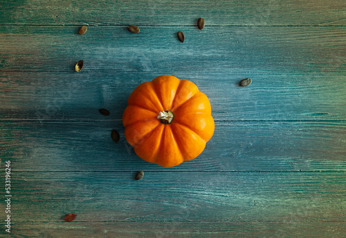 orange pumpkin on blue and colorful wooden background, ideal as a background for Halloween or autumn theme, orange pumpkin isolated