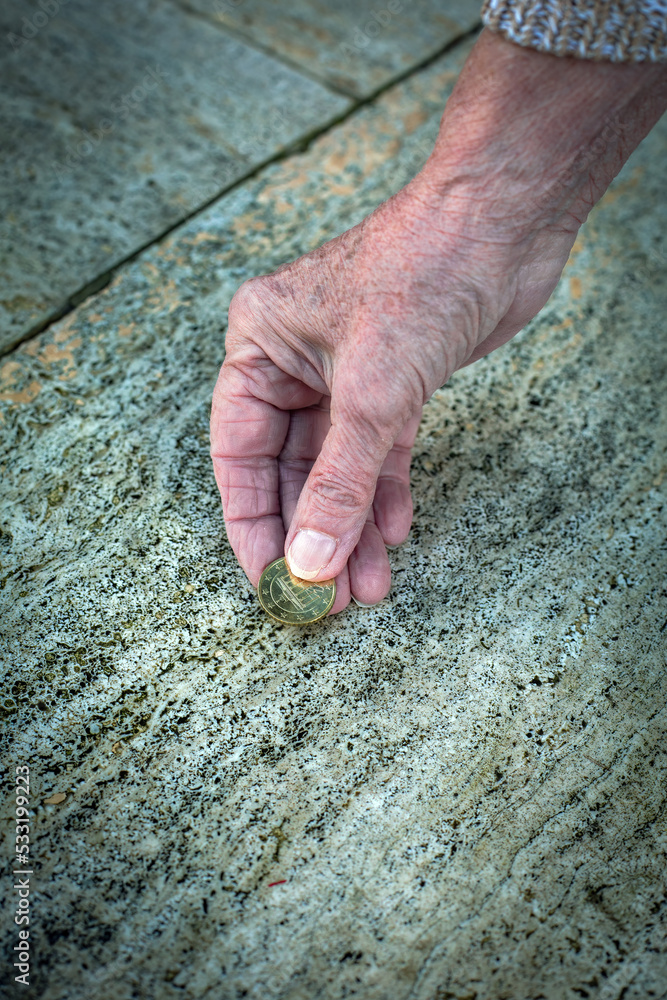 close-up of old womans hand picking up a coin from the floor close-up of old womans hand picking up a coin from the floor