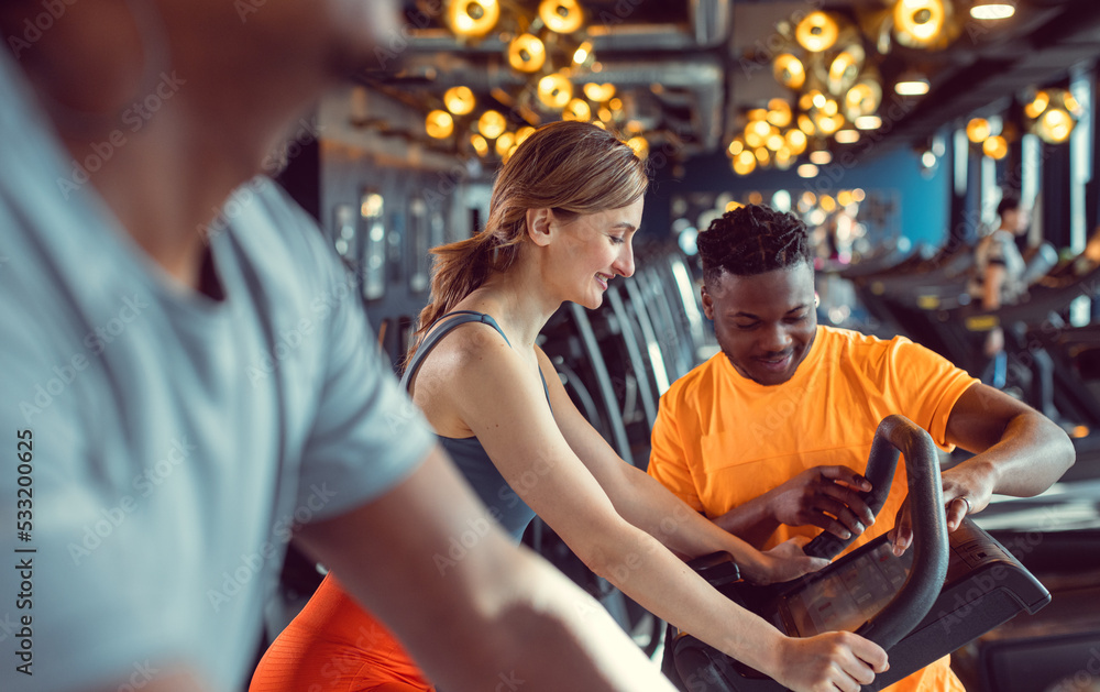 Group of diversity friends, men and woman, exercising on bike in gym