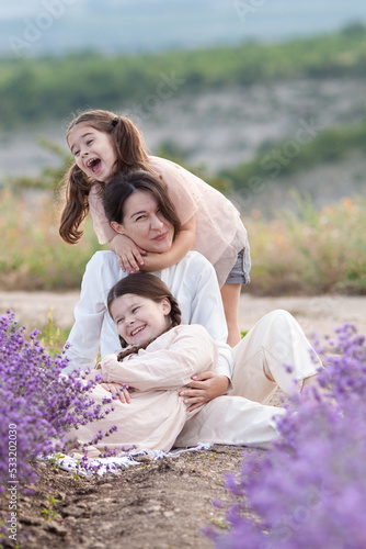 Portrait of a mother with her daughters on a background of lavender, Cozy picnic in a lavender field with mountains in the background