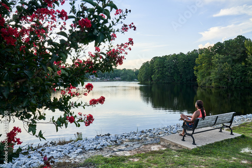 African American Women sitting on bench on lake Peachtree City Georgia , rose tree 
