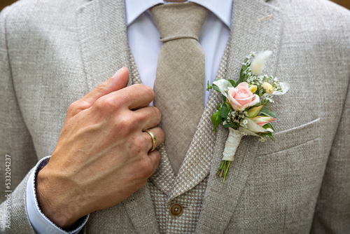 Bräutigam im Anzug mit Ansteckblumen und Ehering photo