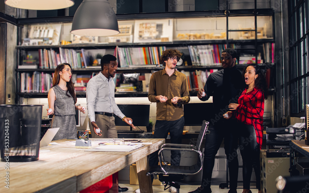 Obraz premium Group diverse multiracial businesspeople wearing casual clothes in modern office, taking break, rest, playing games with relaxation, throwing paper ball to the target. Achievement, Success Concept.