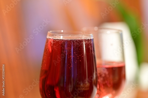 Wine glass with red raspberry juice, cut with water on orange ple with an accent of green - an interesting background