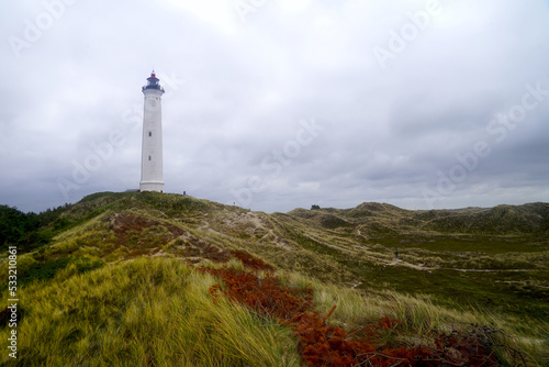 white lighthouse Lyngvig Fyr in a beautiful dune landscape with a sandy trail at a cloudy day, Hvide Sande, Søndervig, Ringkøbing, Denmark