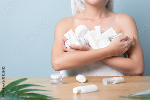Woman holding packaging of cream product many full hands with copy space on light blue pastel background. Skincare and facial clean with various products, product selection, safety skincare product photo