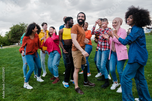 Group of young people from different cultural groups dancing in the park outdoors