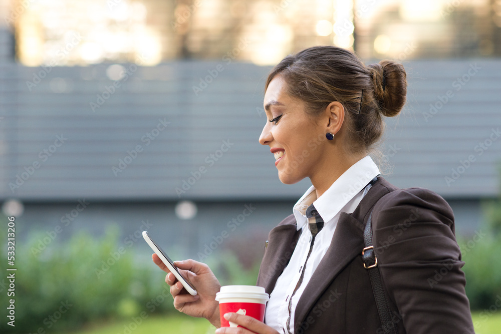 Young smiling businesswoman using phone in front of corporate office building Young smiling businesswoman using phone in front of corporate office building