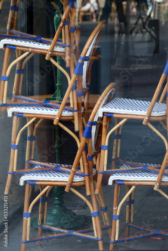 Chairs stacked on top of each other in the window of a closed restaurant