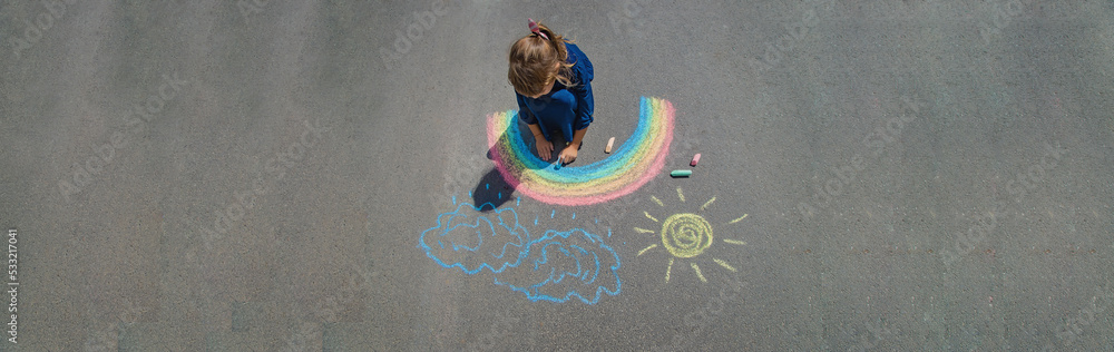 Naklejka premium child draws with chalk on the pavement. Selective focus.