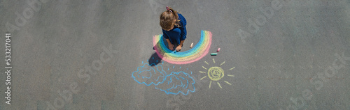child draws with chalk on the pavement. Selective focus.