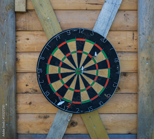 darts stuck in a dartboard on wooden wall photo