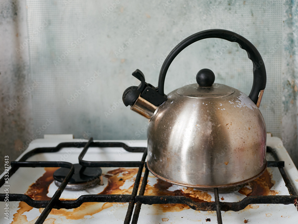 Dirty home cooking stove with old metal kettle, natural look. Gas stove with stains after cooking. Dirty home cooking stove with old metal kettle, natural look. Gas stove with stains after cooking.