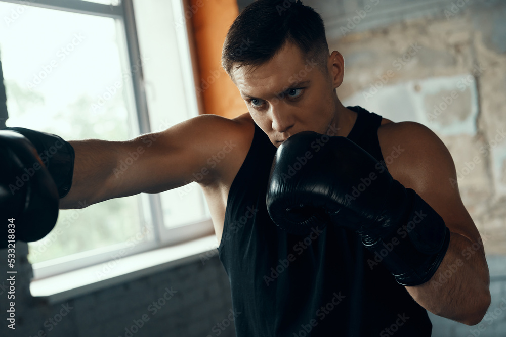 Concentrated young man practicing in punching while standing in gym