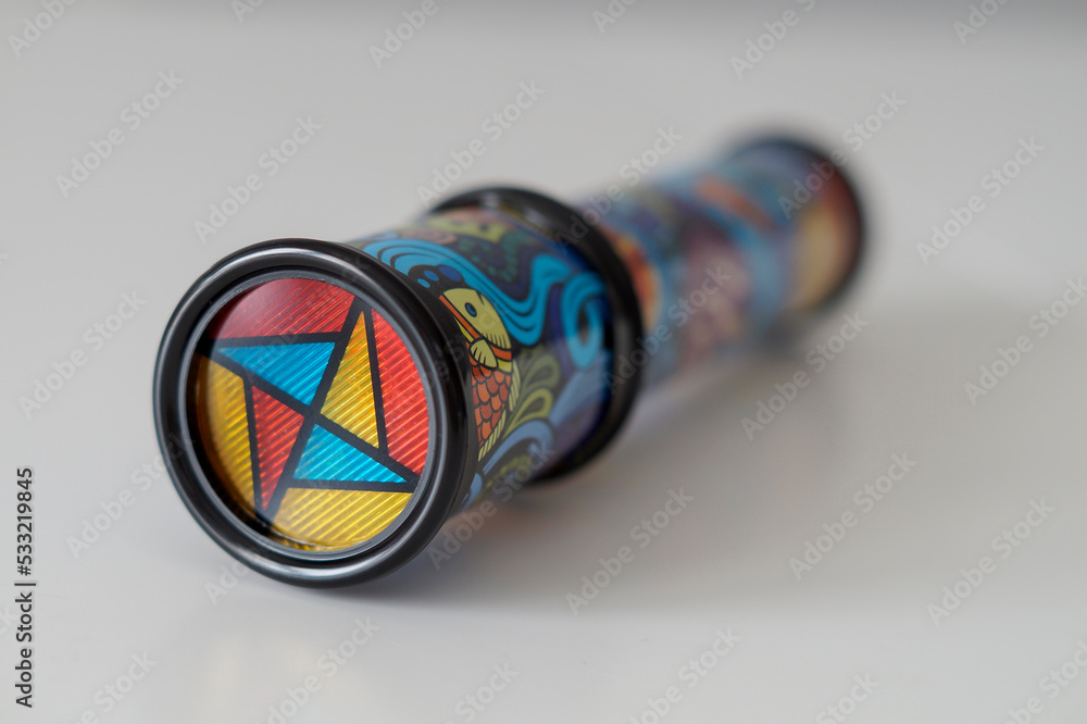Close-up of a kid's kaleidoscope toy used to create abstract images while looking through the viewfinder. Selective focus. - obrazy, fototapety, plakaty 