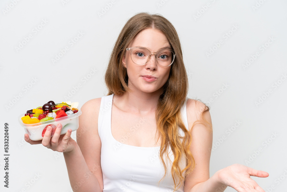 Young pretty woman holding a bowl of fruit isolated on white background making doubts gesture while lifting the shoulders Young pretty woman holding a bowl of fruit isolated on white background making doubts gesture while lifting the shoulders