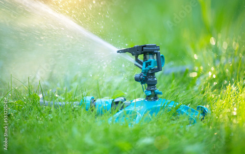 Sprinkler head watering green grass lawn. Gardening concept. Smart garden activated with full automatic sprinkler irrigation system working in a green park. Outdoors