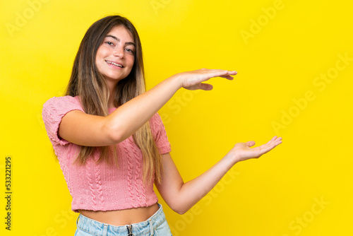 Young caucasian woman isolated on yellow background holding copyspace to insert an ad © luismolinero