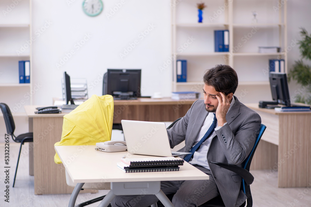 Young male employee looking after new born at workplace