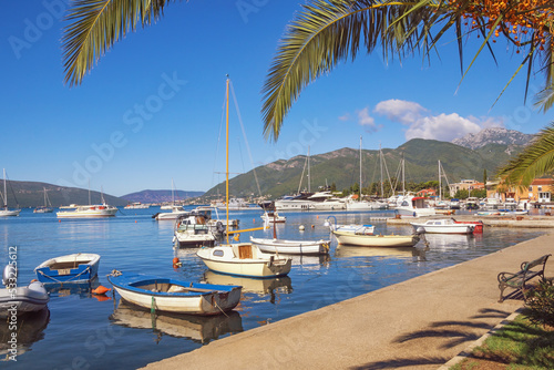Beautiful autumn Mediterranean landscape with village embankment and fishing boats on water. Montenegro, Adriatic Sea, view of Bay of Kotor  and Seljanovo village near Tivat city