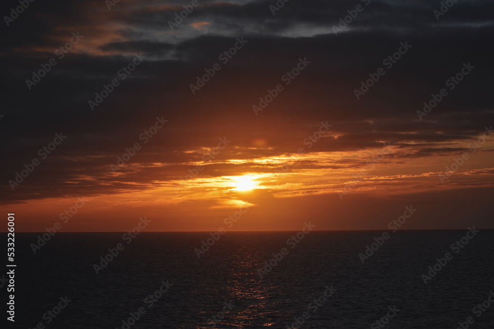 bright orange yellow sunrise sunset over ocean reflection in sea 