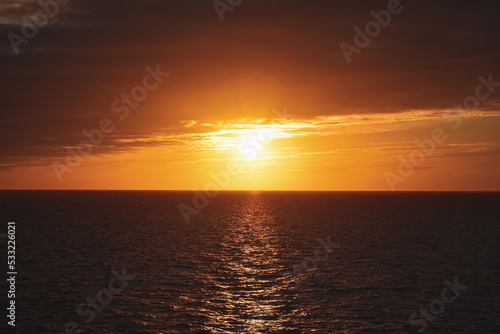 Fototapeta Naklejka Na Ścianę i Meble -  orange yellow blue sunrise sunset reflection over ocean sea 