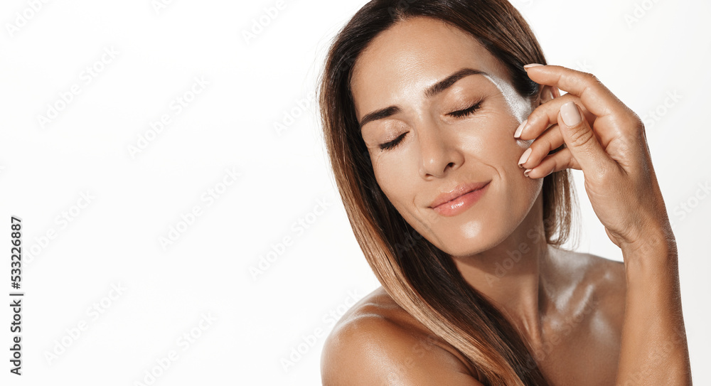 Smiling middle-aged woman touching her soft, glowing skin with pleasure. Female model using anti-aging hyaluronic skin treatment after shower, white background Smiling middle-aged woman touching her soft, glowing skin with pleasure. Female model using anti-aging hyaluronic skin treatment after shower, white background