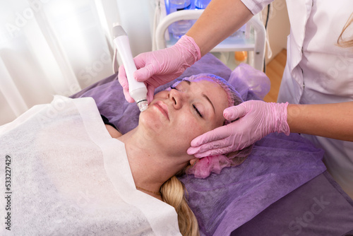 Beautiful woman getting face vacuum procedure for healthy skin in spa salon. 