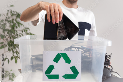 Man throwing away broken mobile phones in recycle container. Hazardous E-Waste Recycling. Waste Electrical and Electronic Equipment.