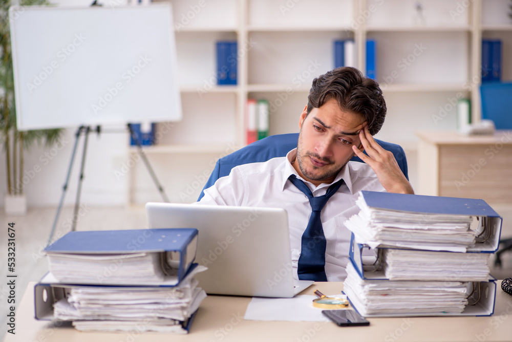Young male employee and too much work in the office Young male employee and too much work in the office