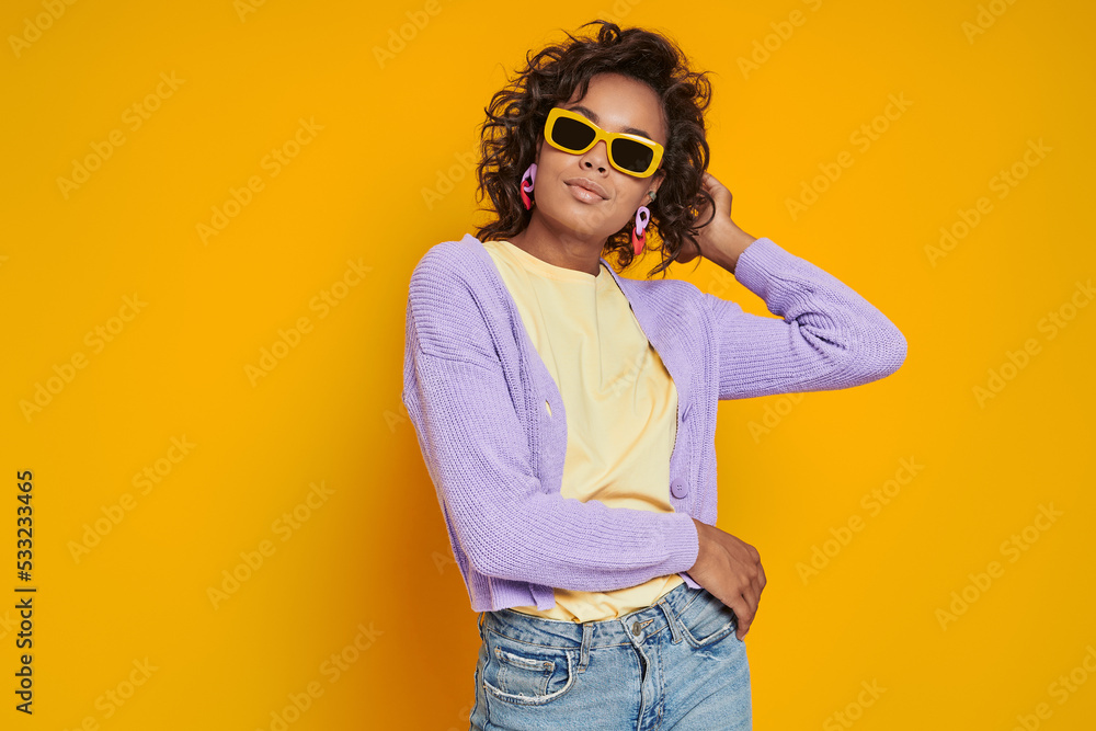 Beautiful African woman in funky eyeglasses standing against yellow background Beautiful African woman in funky eyeglasses standing against yellow background