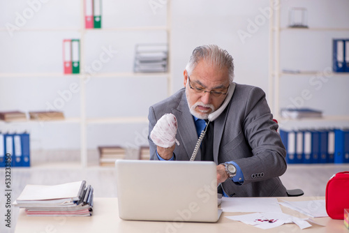 Old male employee cutting his hand in the office