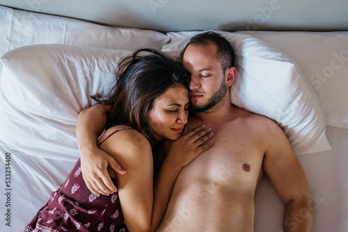 aerial view of the heads of a latin couple sleeping cuddled together in a bed