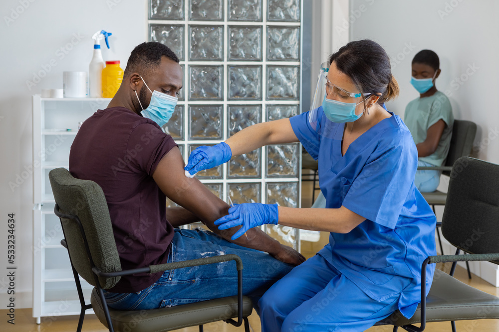 Fototapeta premium Black man with face mask being vaccinated