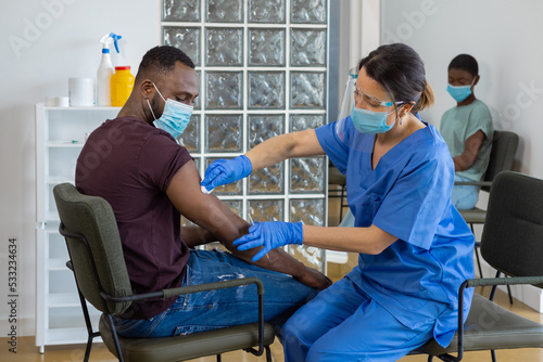Foto Black man with face mask being vaccinated