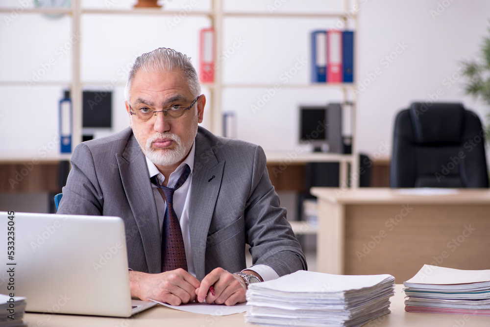 Old male employee unhappy with excessive work in the office Old male employee unhappy with excessive work in the office