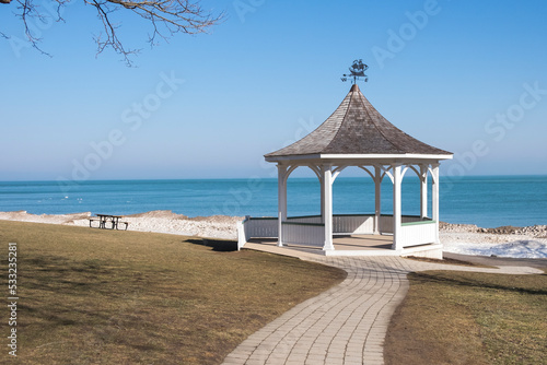 A picnic table sits beside a white gazebo in Queen's Royal Park in Niagara on the Lake Ontario Canada. photo