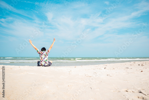Man sits on the beach during the summer time enjoying the view.