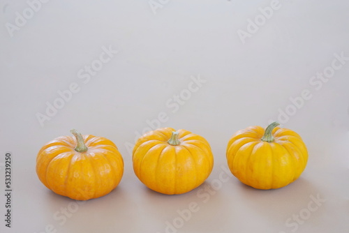 Three Orange Pumpkins in a Row on Beige Background