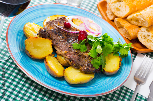 Appetizing beef steak with slices of baked potato and parsley