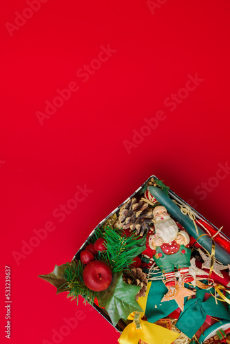box with decorations and christmas figures messed up on red background. christmas time.