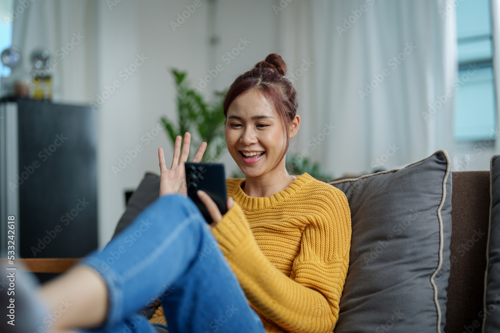 portrait of a young Asian woman woman holding smartphone while sitting on sofa portrait of a young Asian woman woman holding smartphone while sitting on sofa