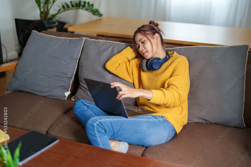 Fototapeta premium Portrait of a young Asian woman using a computer on the sofa