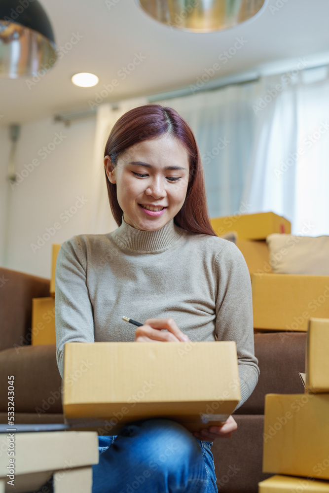 A portrait of a small startup, an SME owner, an Asian female entrepreneur checking orders to arrange the produce before packing the products in the inner boxes with the customers. Freelance concepts A portrait of a small startup, an SME owner, an Asian female entrepreneur checking orders to arrange the produce before packing the products in the inner boxes with the customers. Freelance concepts
