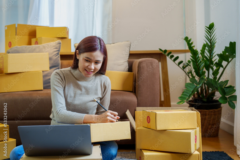 A portrait of a small startup, an SME owner, an Asian female entrepreneur checking orders to arrange the produce before packing the products in the inner boxes with the customers. Freelance concepts A portrait of a small startup, an SME owner, an Asian female entrepreneur checking orders to arrange the produce before packing the products in the inner boxes with the customers. Freelance concepts