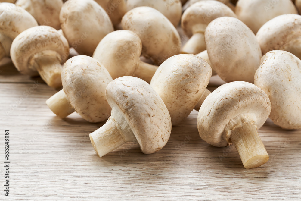 whole champignon mushrooms on a white wooden background close-up. whole champignon mushrooms on a white wooden background close-up.